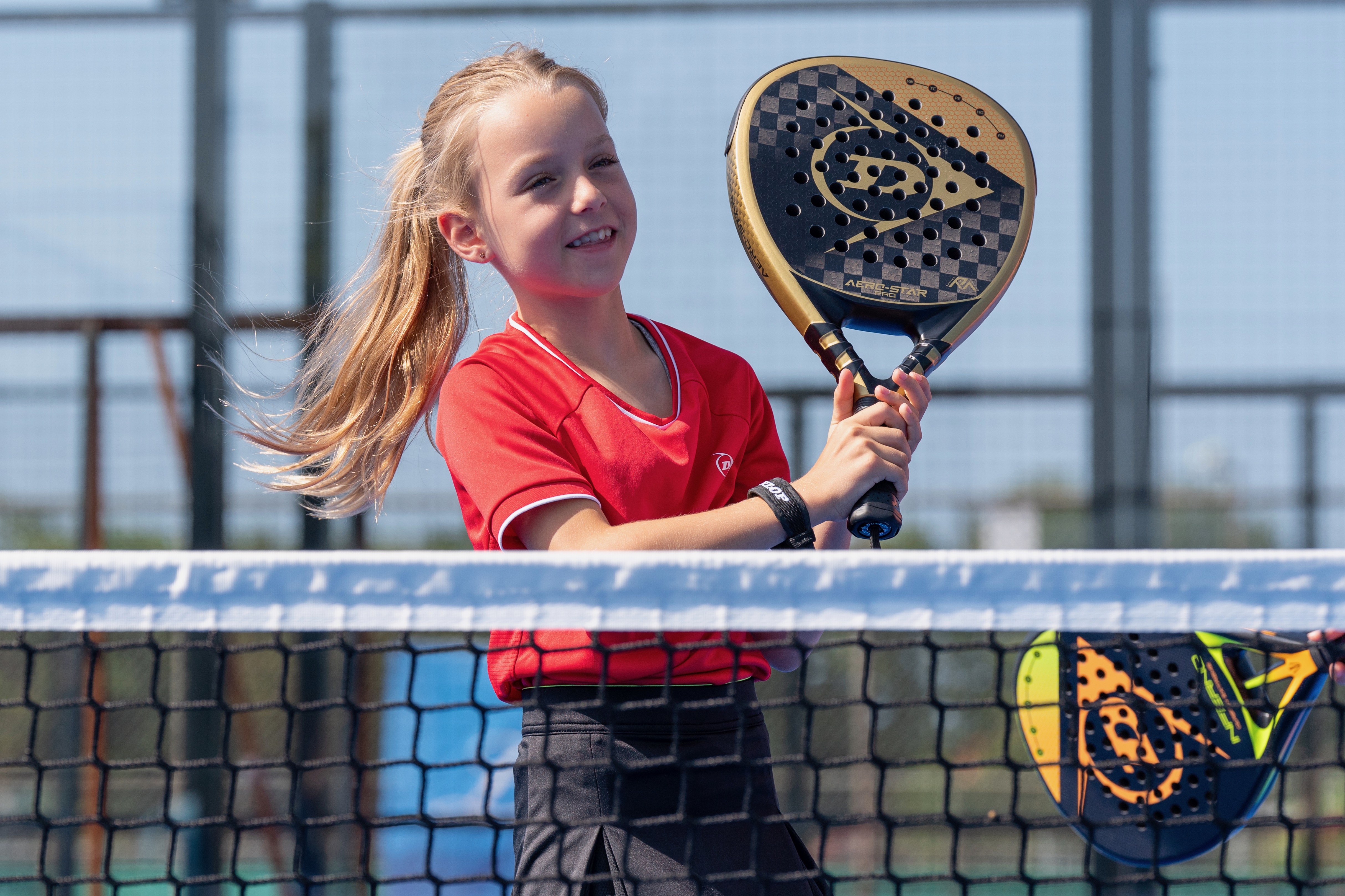 Meisje met padelracket aan het net